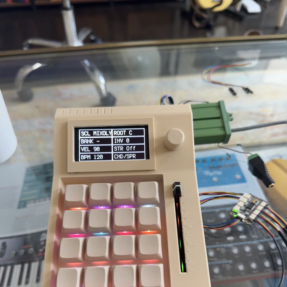 The R1C1 from above with every key lit a different colour and the OLED showing SCL MIXOLY, ROOT C, VEL 90, BPM 120.