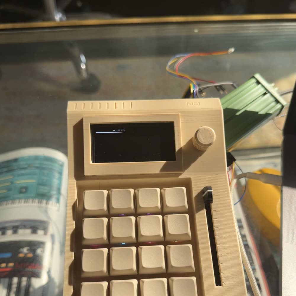 The R1C1 on a glass desk in low sun, showing the vent slots, encoder knob and the slider channel.